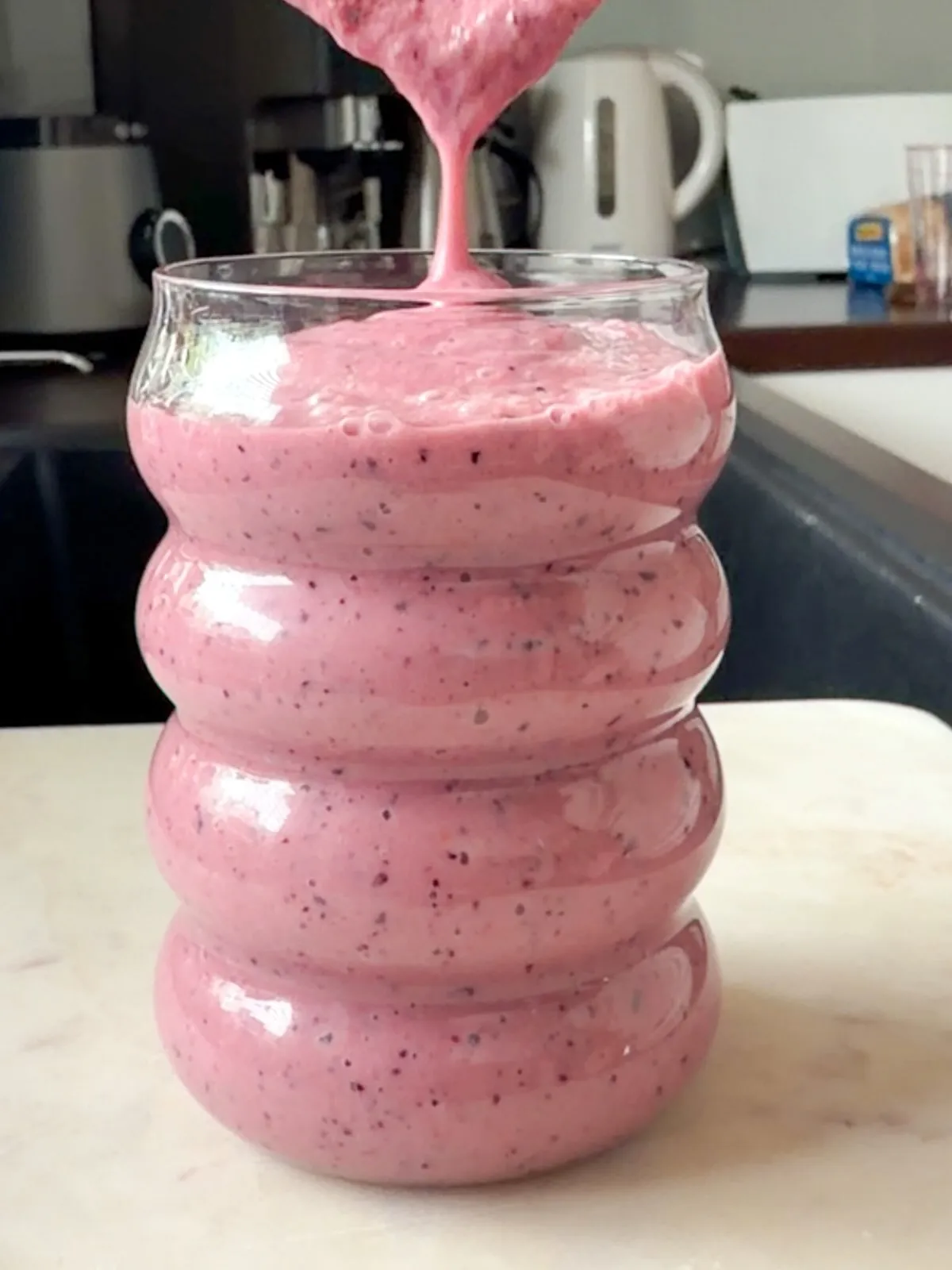 Banana Avocado Berries Smoothie Pouring into a Tall Glass