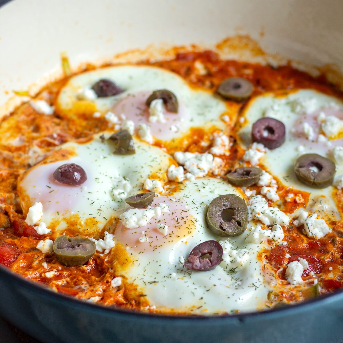 Easy Shakshuka with leeks served in a pan with olives on top.