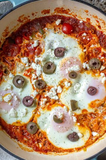 Easy Shakshuka with leeks served in a pan with olives on top.
