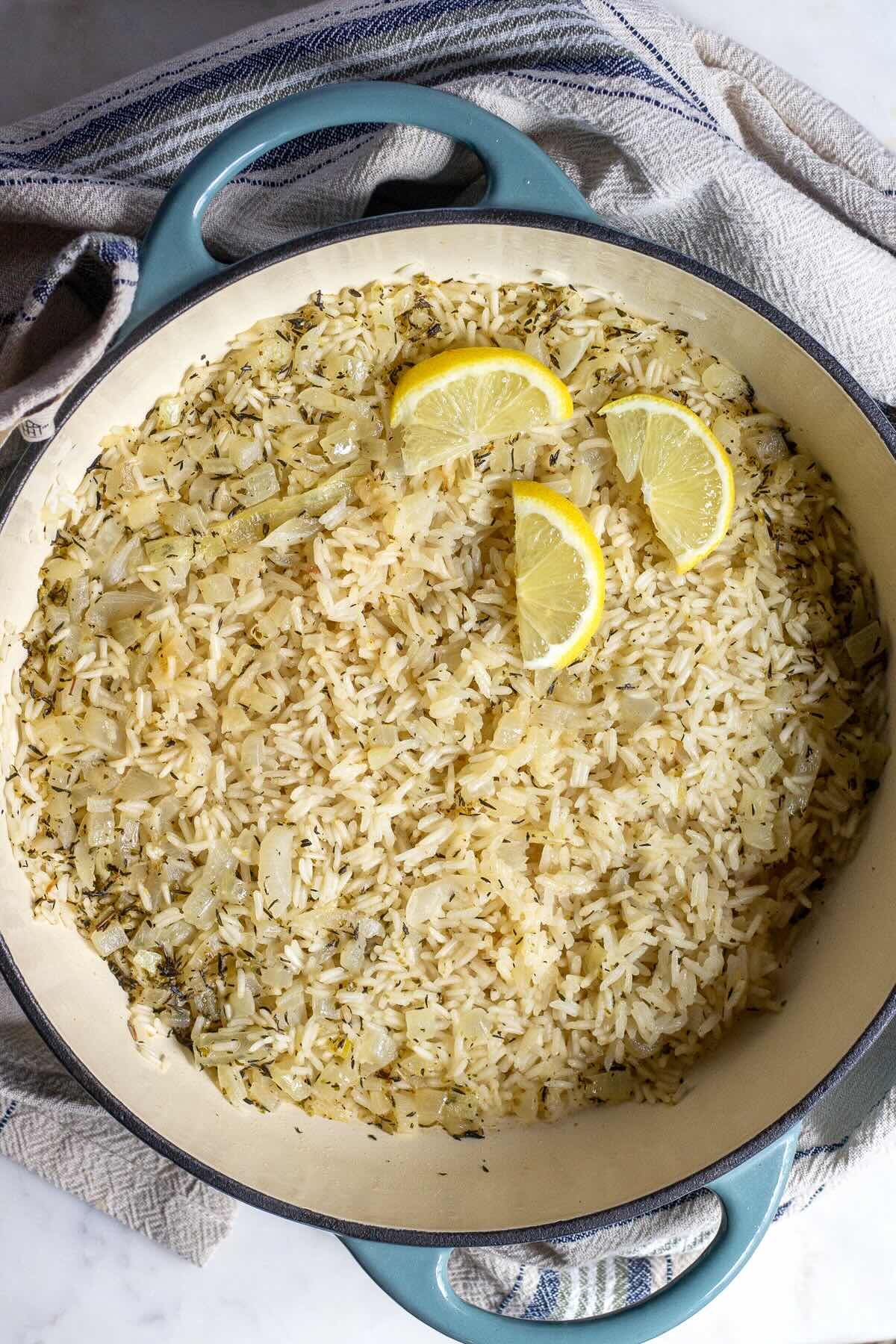 Mediterranean rice recipe, cooked rice shown in a Dutch oven skillet and decorated with lemon wedges. 