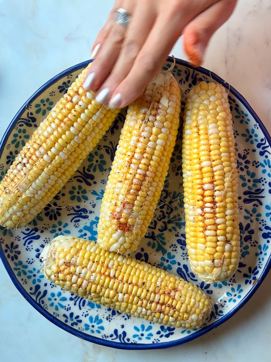 Ninja air fryer corn on the cob, coat corn with seasonings.