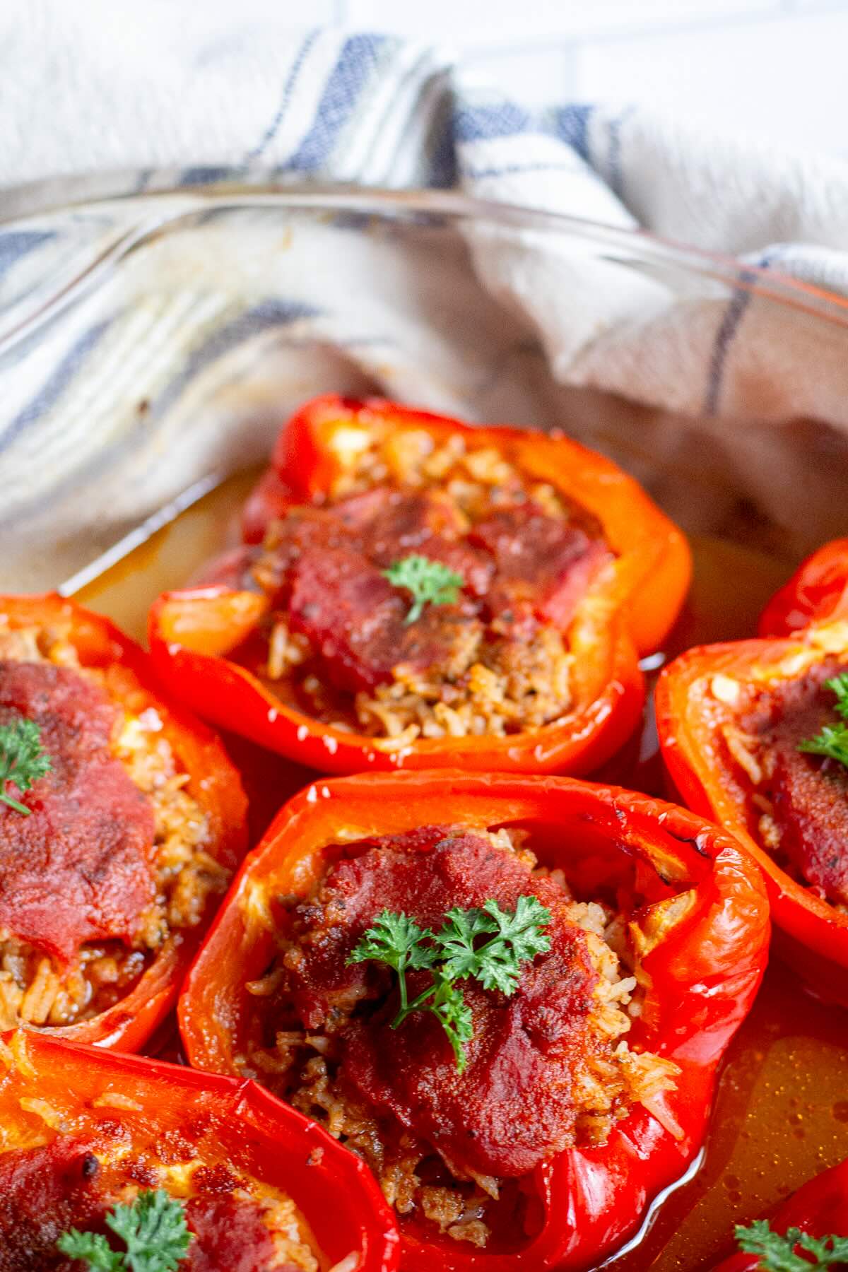 Homemade gluten-free meat and rice stuffed peppers baked in a tomato sauce and topped with fresh herbs.
