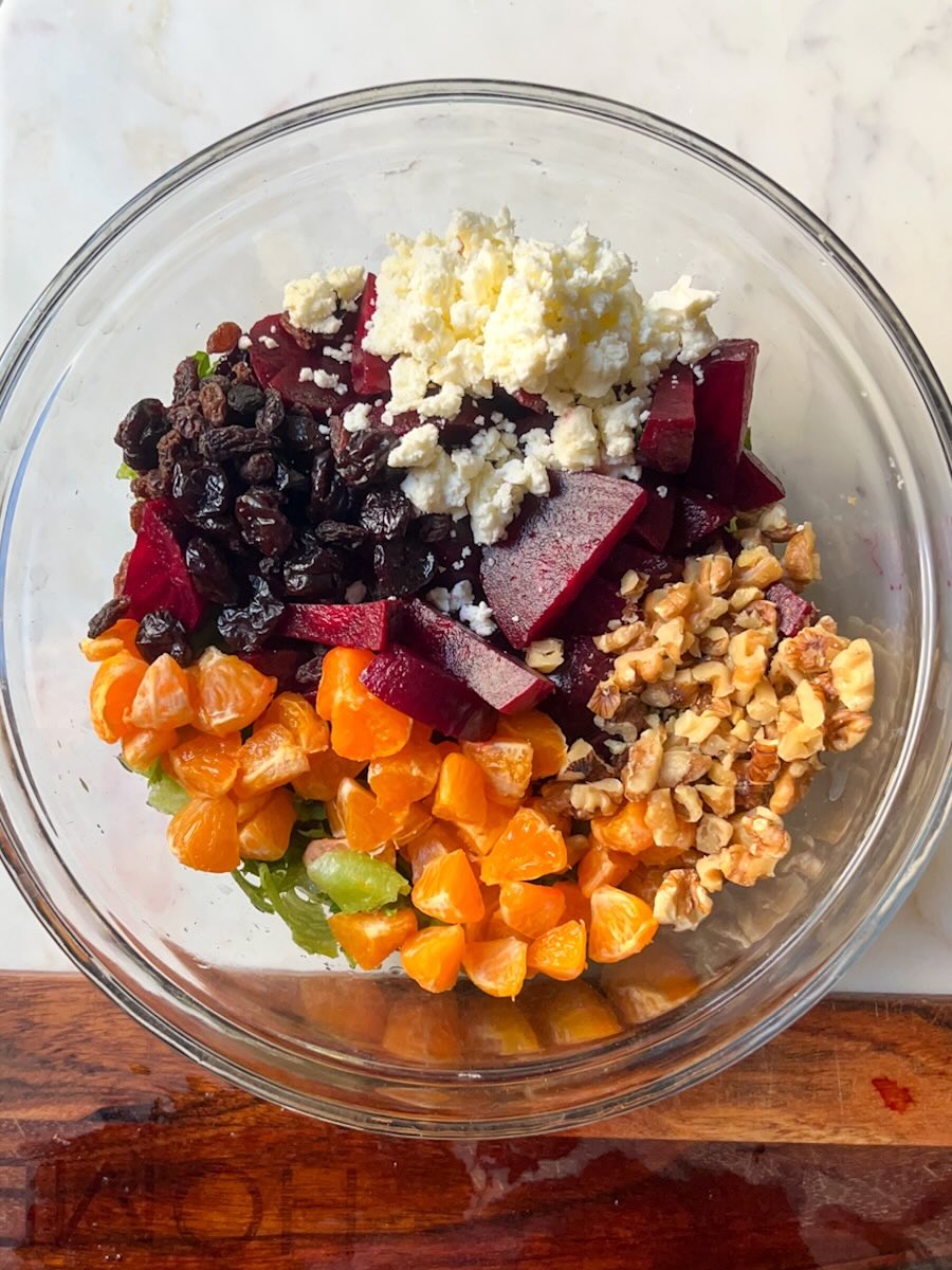 Beet Salad with Mandarin Oranges, Combine the mixed greens, cooked beet slices, mandarin oranges, chopped walnuts, and dried cranberries in a large salad bowl.