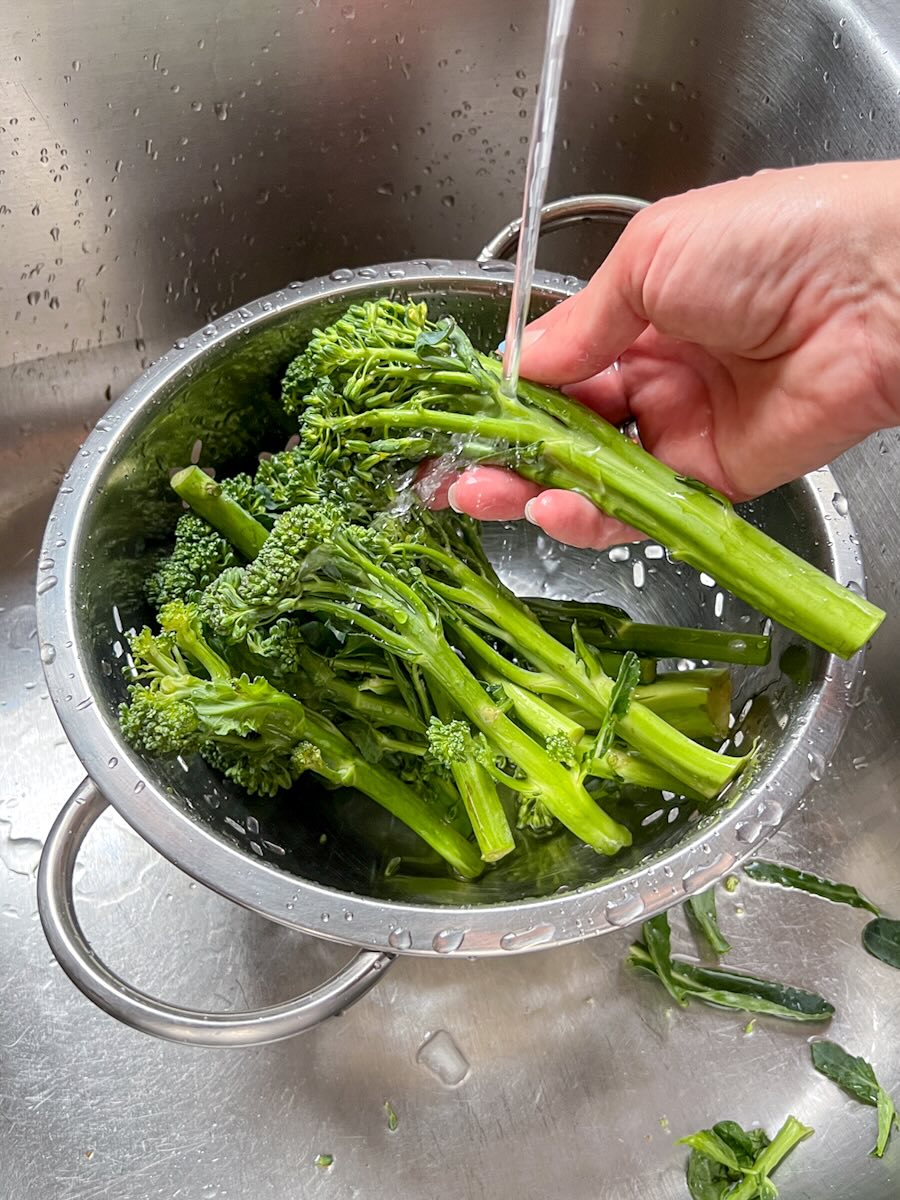 Steamed Broccolini with garlic and lemon, wash broccolini under running water.