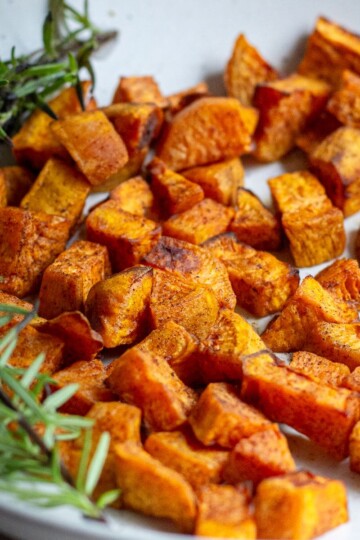 Sweet Potato Cubes with Cinnamon served on a plate with rosemary