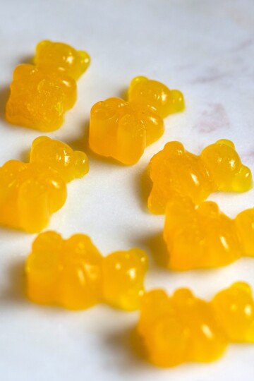 A close-up of bright orange turmeric ginger gummy bears, displayed on a white plate, made with natural ingredients.