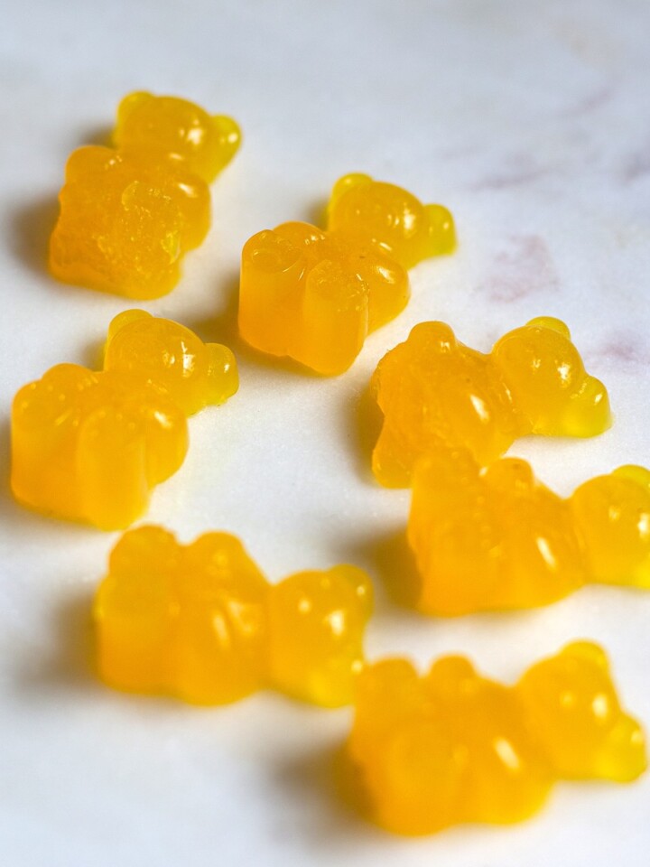 A close-up of bright orange turmeric ginger gummy bears, displayed on a white plate, made with natural ingredients.