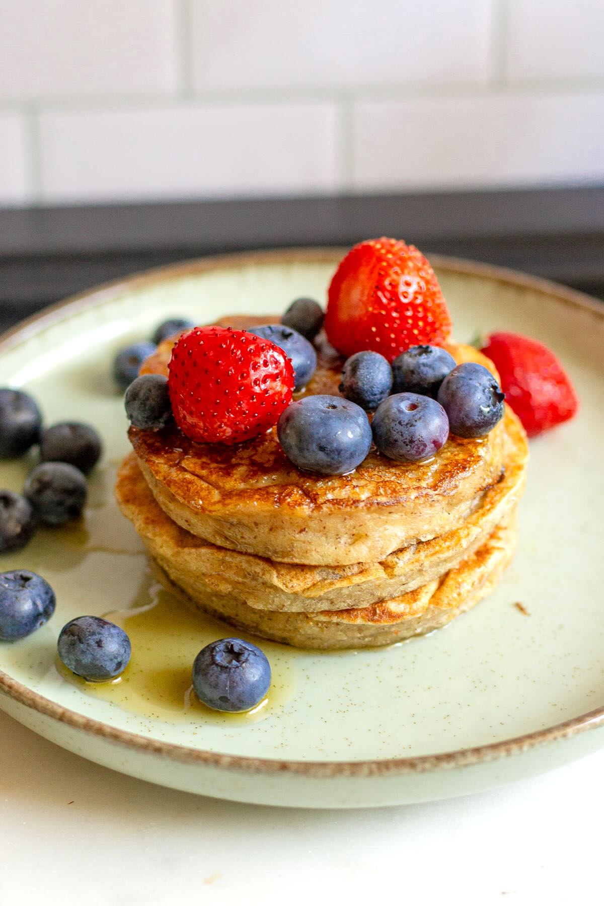 Banana pancakes with maple syrup, strawberries and blueberries.