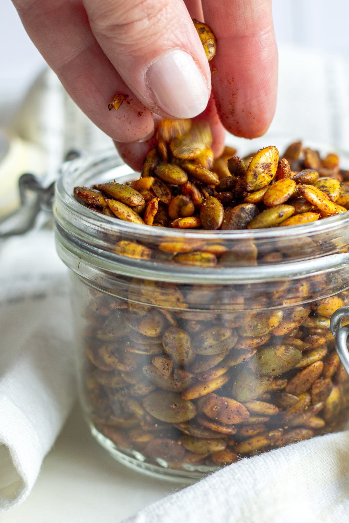 Roasted pumpkin seeds coated in turmeric spice blend in a jar.