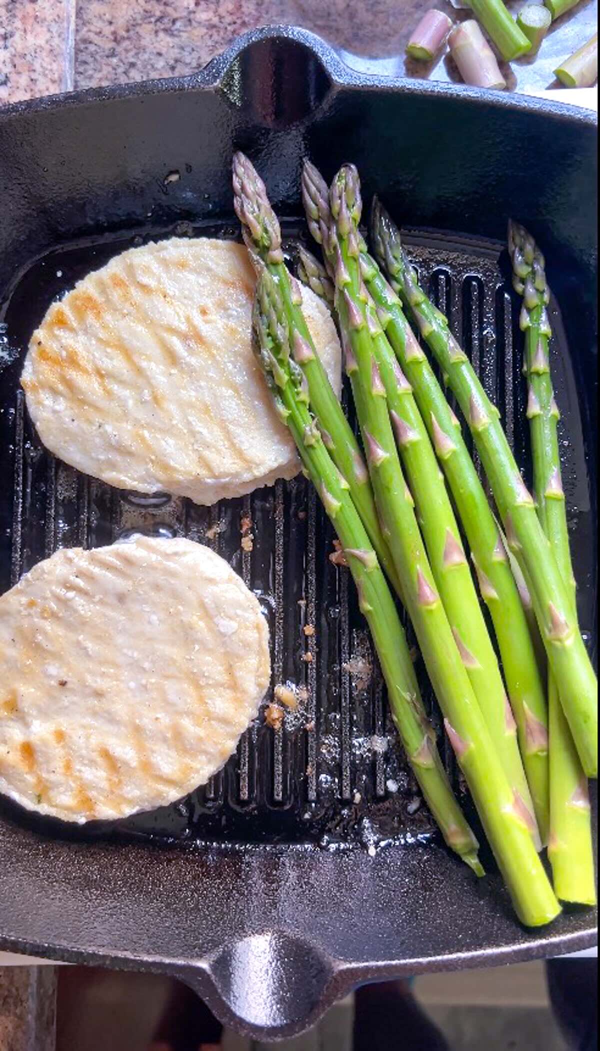 Mahi mahi burgers with grilled asparagus shown on the grill pan