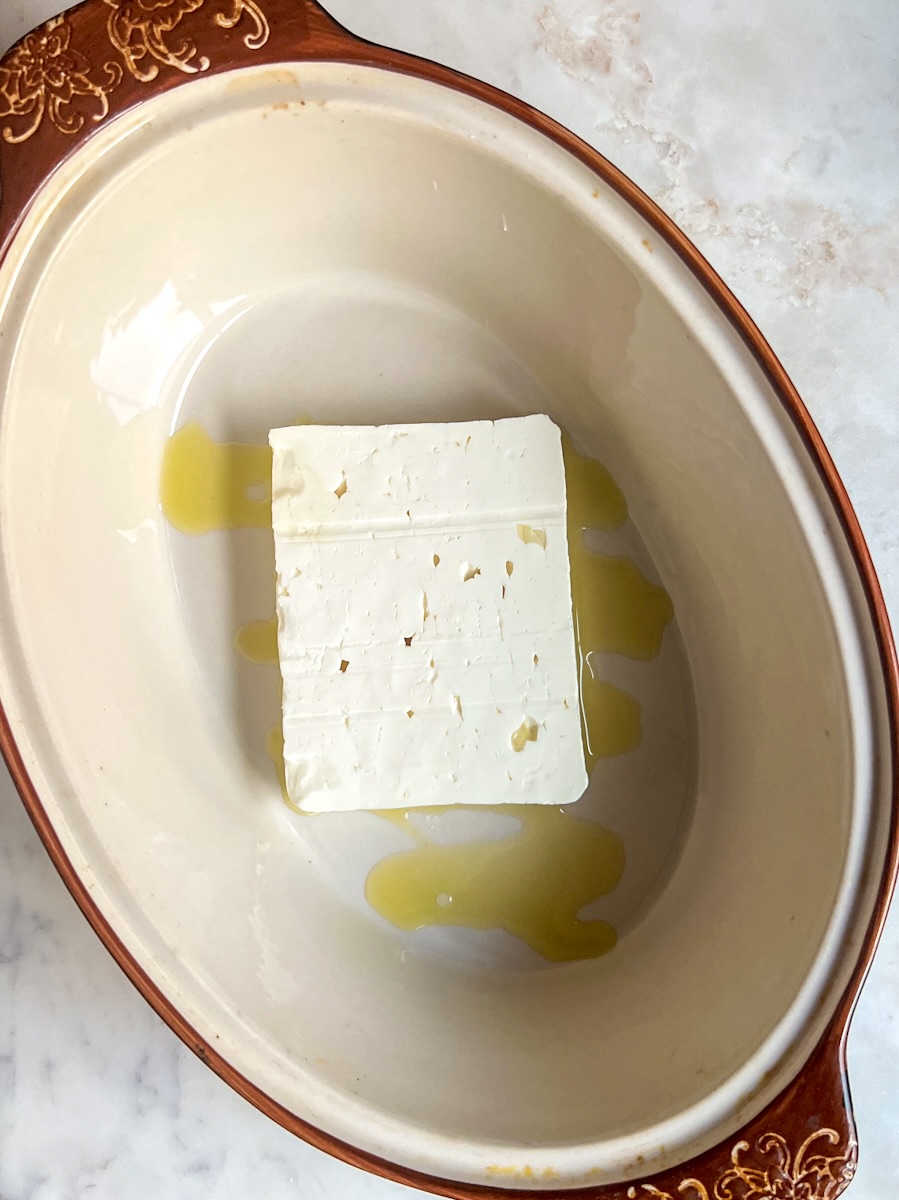 Baked feta pasta, add olive oil and block of feta to a baking dish.