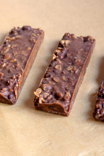 Hero image of homemade granola bars made without peanut butter, stacked on a plate, showing a close-up of their texture with chocolate chips and oats visible.