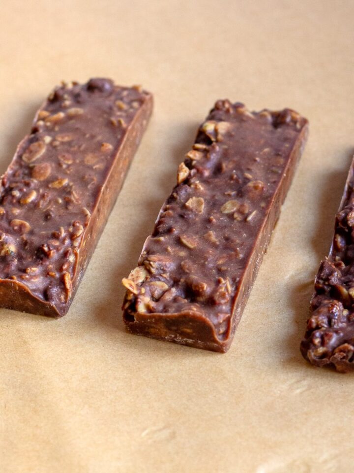 Hero image of homemade granola bars made without peanut butter, stacked on a plate, showing a close-up of their texture with chocolate chips and oats visible.
