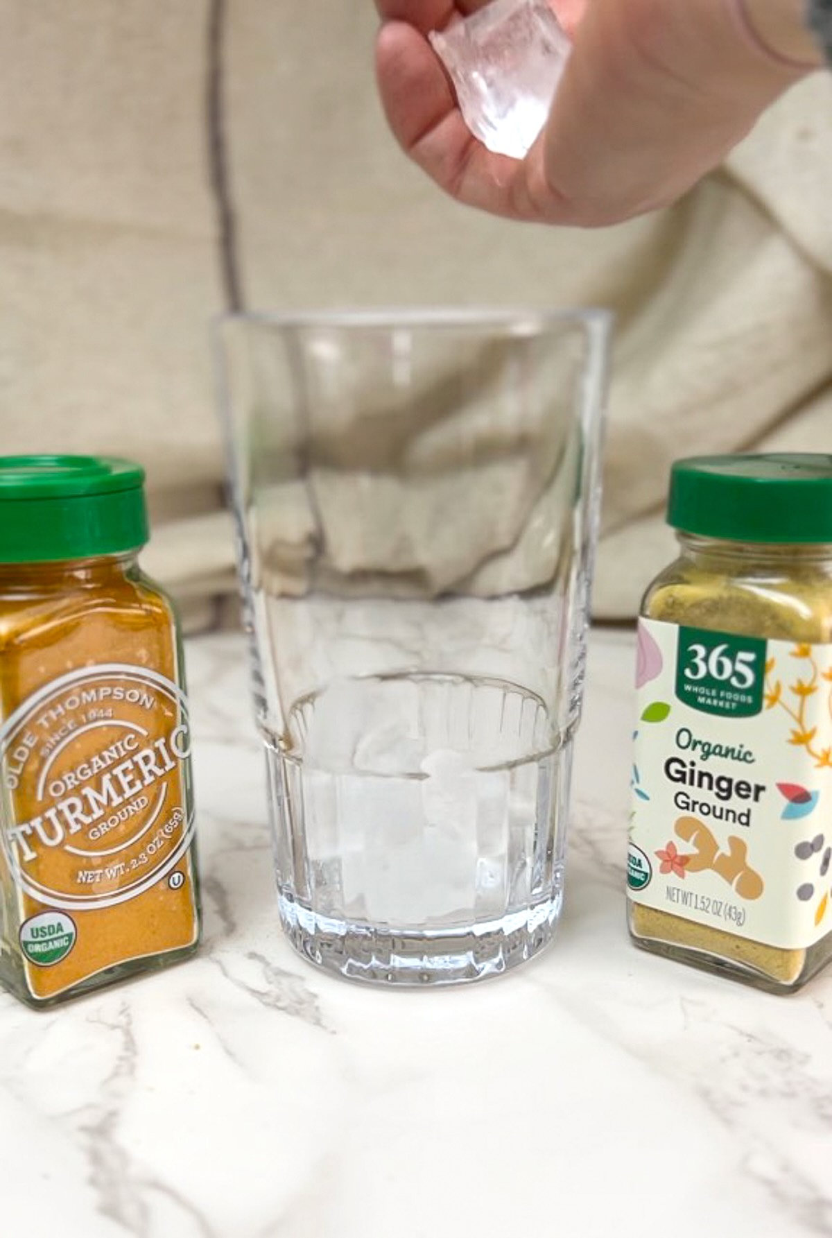 Morning meditation juice preparation, adding ice cubes to a tall glass.