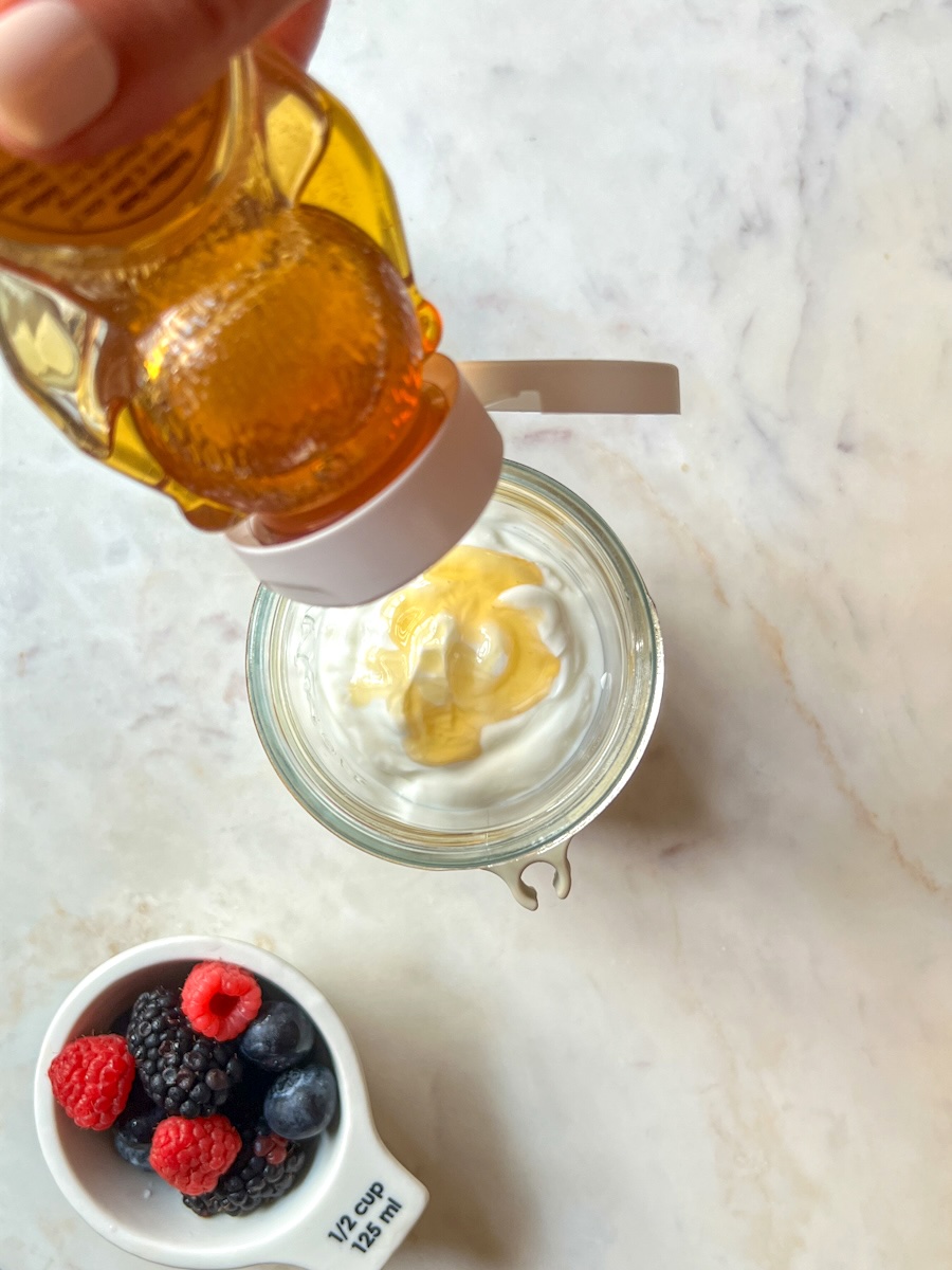 Greek Yogurt, fruit and nuts parfait, add honey to the Greek yogurt.