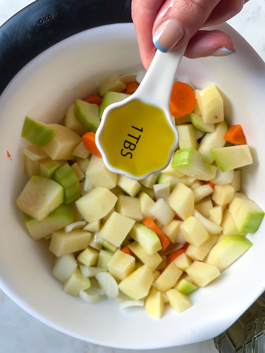 Oven roasted potatoes and carrots with onion and zucchini, add oil to chopped vegetables.