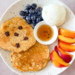 Fluffy gluten-free pancakes topped with maple syrup and served with fruits