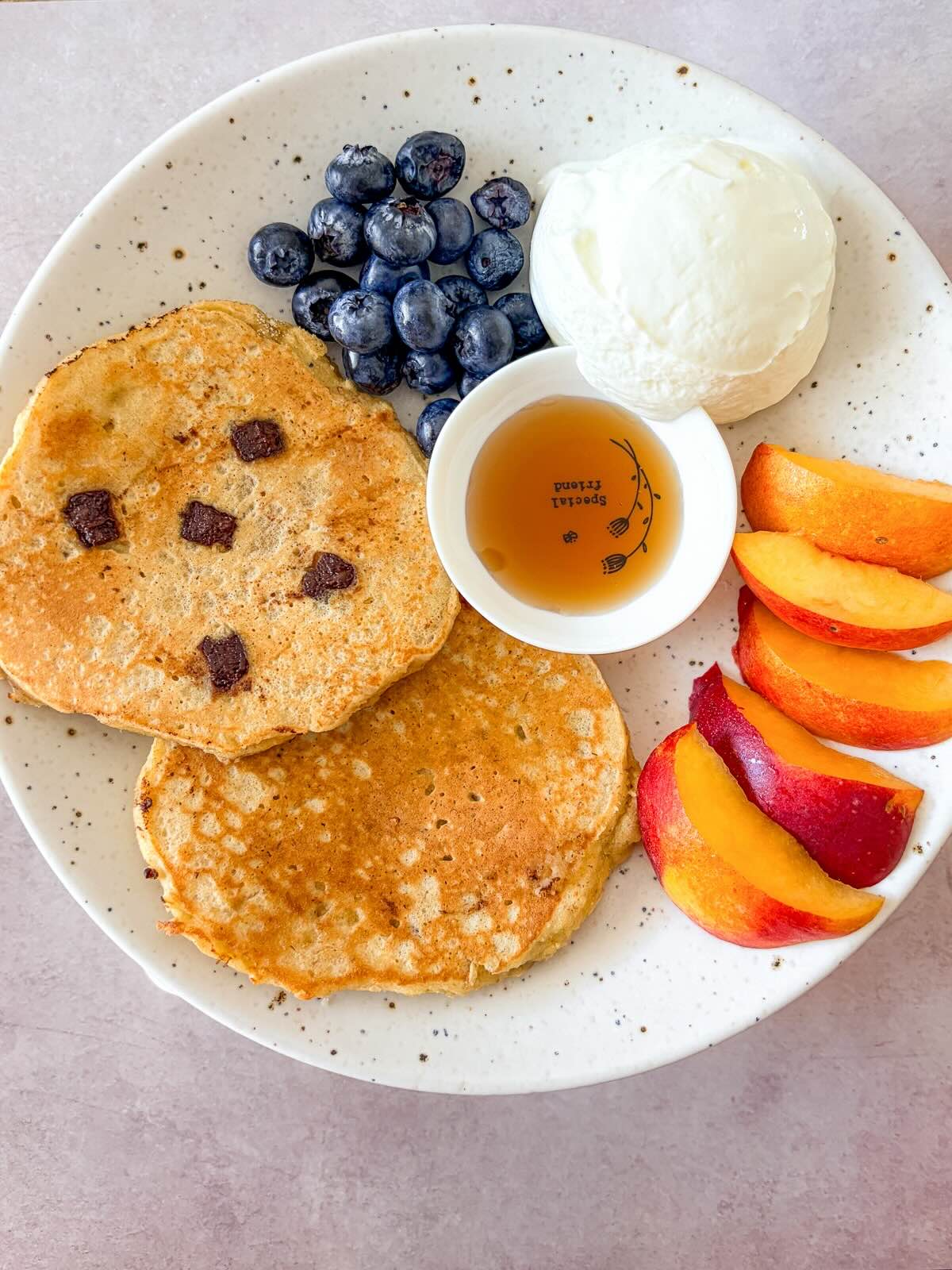 Fluffy gluten-free pancakes topped with maple syrup and served with fruits.